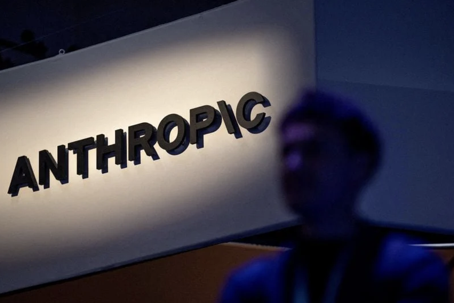 Fachada da Anthropic com logotipo preto iluminado e pessoa desfocada em primeiro plano, ilustrando notícia sobre prejuízo contábil da empresa de inteligência artificial.