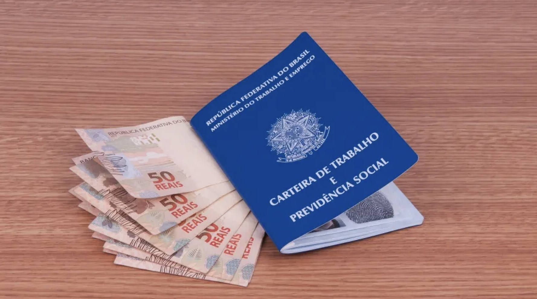 Carteira de Trabalho e Previdência Social azul sobre notas de 50 reais, representando o pagamento do 13º salário em 2026 e os direitos trabalhistas.